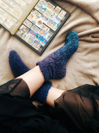 Knitted blue ombre bed socks and oldschool posmark album on bed