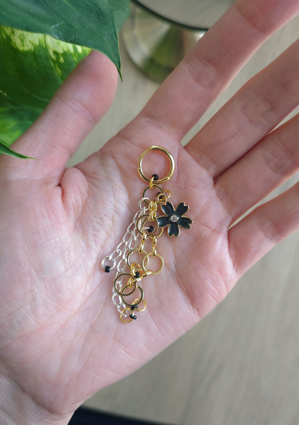 Melnu, zelta toņu auskars, kas novietots plaukstā 
