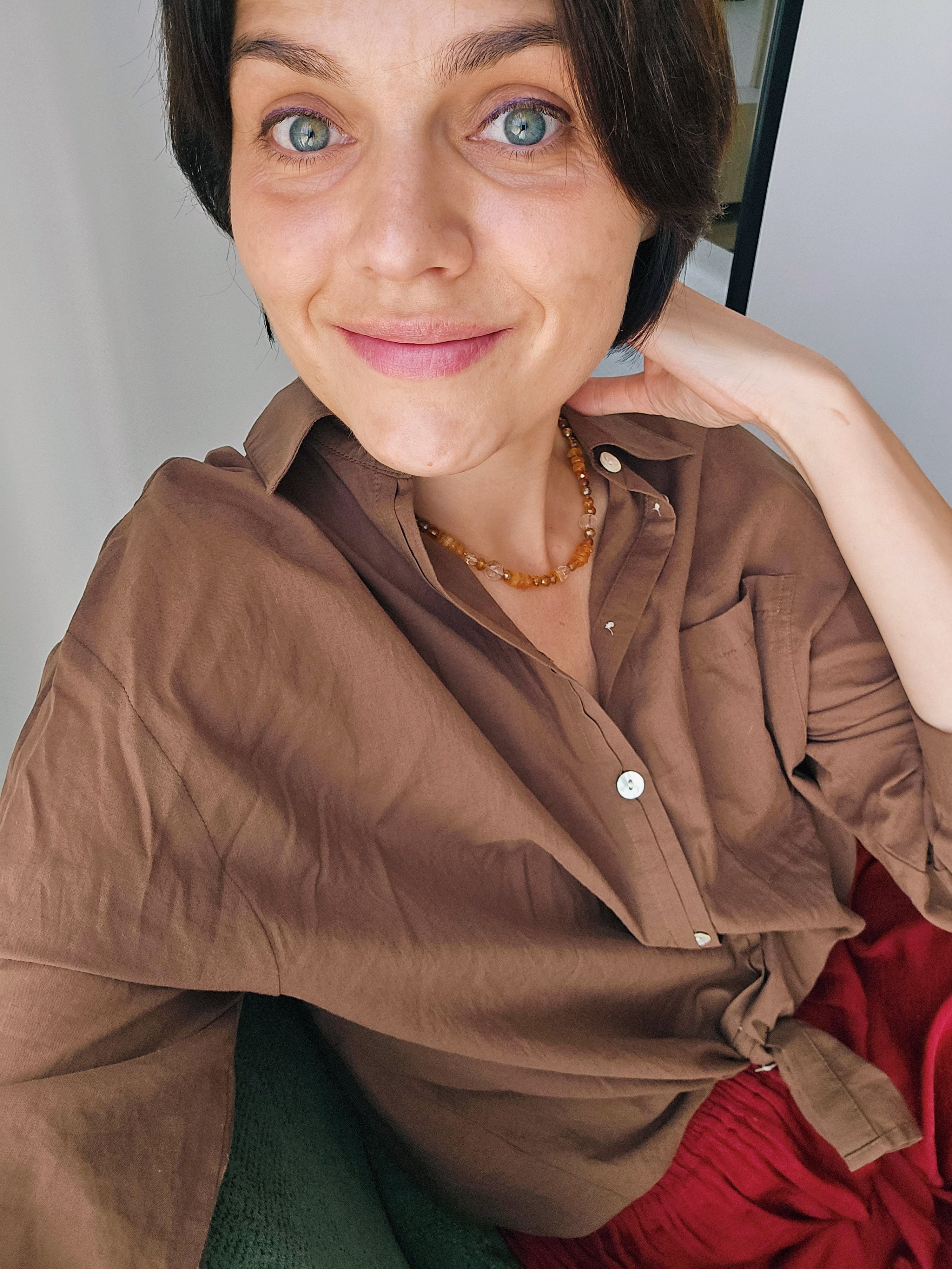 Women in brown zara shirt and orange necklace sitting in green armchair