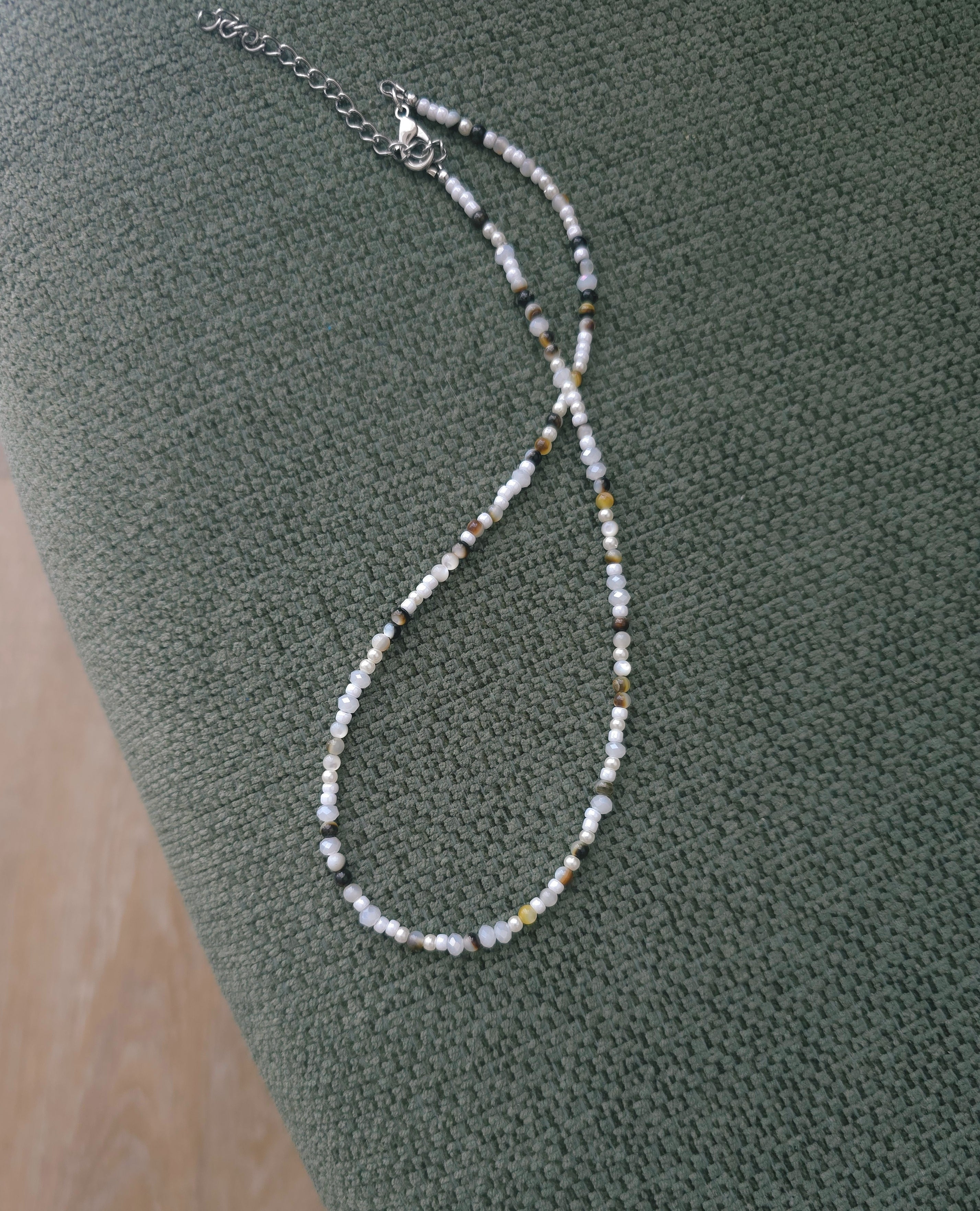 Balta kaklarota ar perlamutra brūniem akcentiem. 