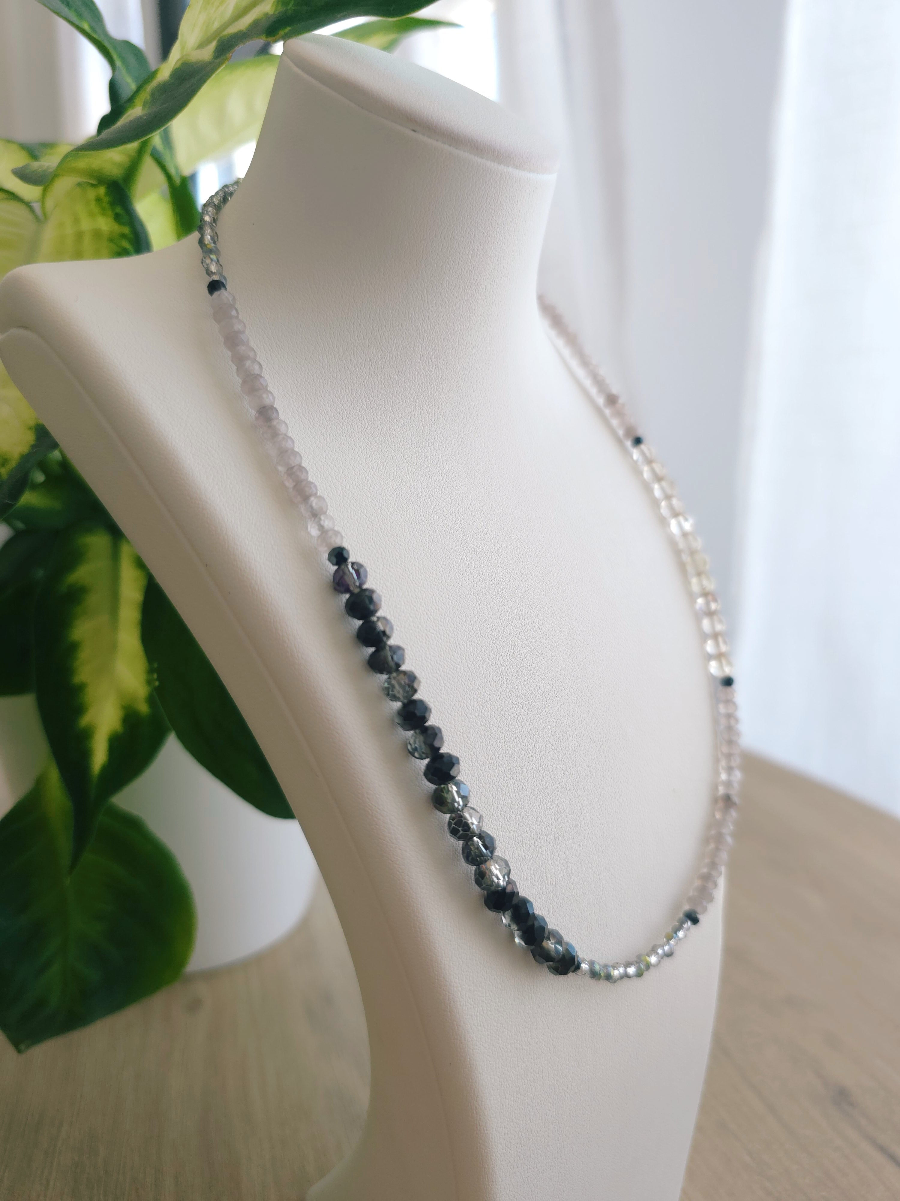 Latvijas pelēkā  mirdzoša kreļļu virtene sievietēm. Balts rotu statīvs uz kafijas galdiņa. 