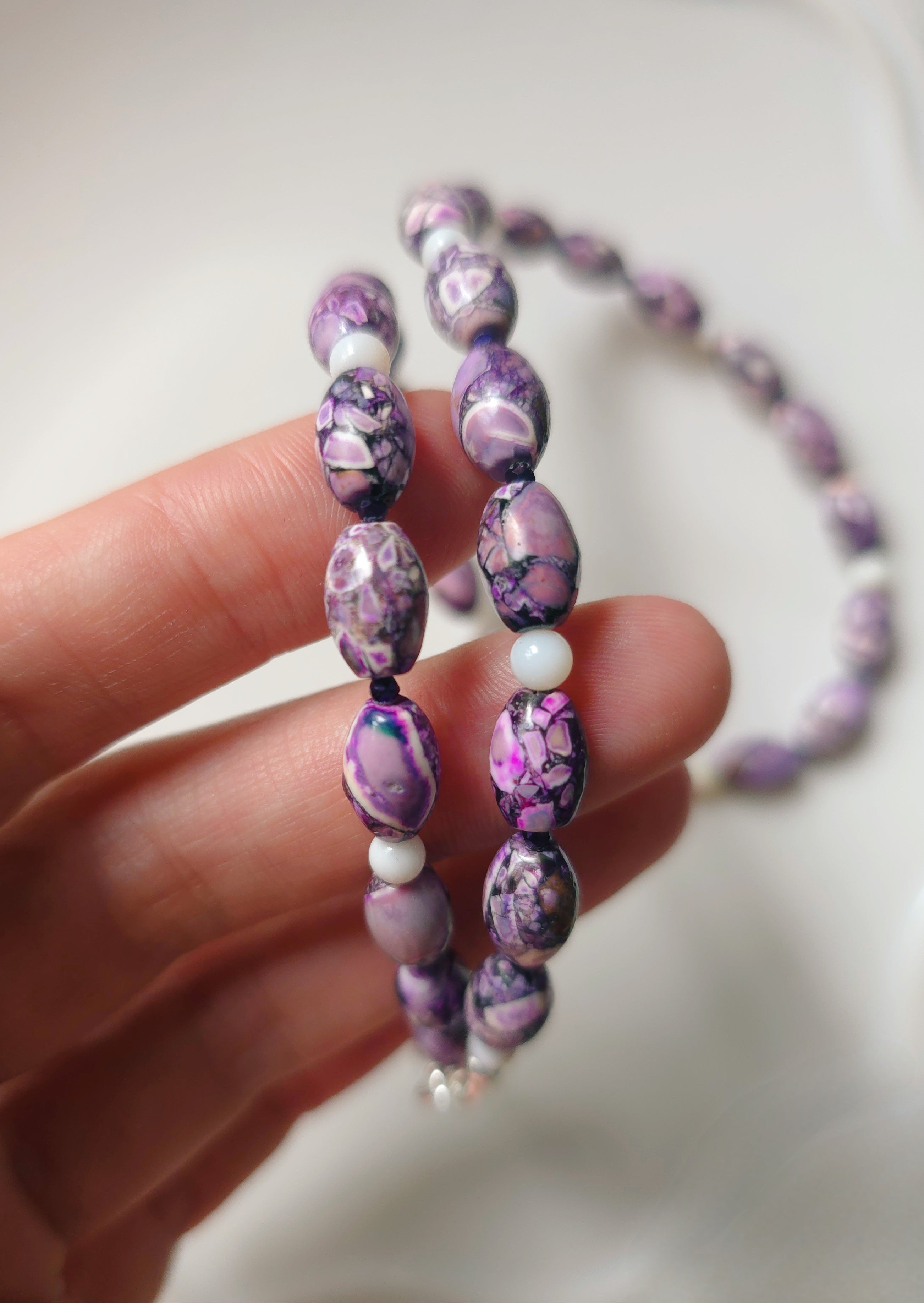 sievietes roka tur violetu kaklarotu
